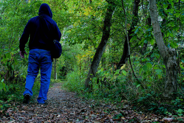 istock Man in hoodie hiking through woods. 1728178838