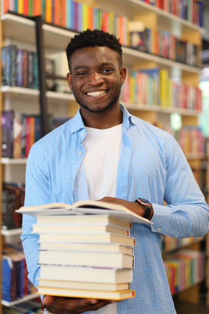 istock A happy young student in a university library, studying amidst bookshelves, holding textbooks, exuding intelligence and joy. 1728207027