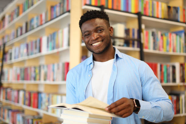 istock A young, happy student in a library at a university, studying with a smile, holding textbooks and notes. 1728207029