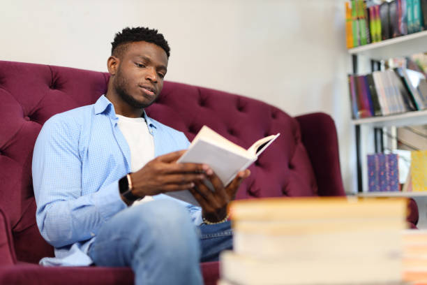 istock A young man with an afro hairstyle, studying and reading a textbook in a modern home library. 1728207546