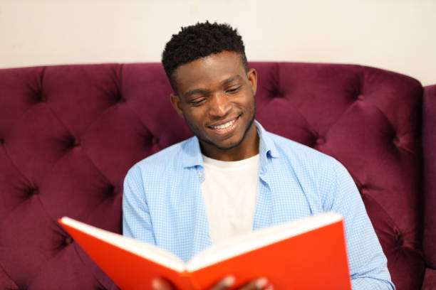 istock A content young man, sitting in a library, holding a book, exudes happiness while studying. 1728207563