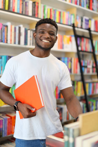istock A smiling young student in a university library, surrounded by books on a bookshelf, radiates positive intelligence. 1728208120