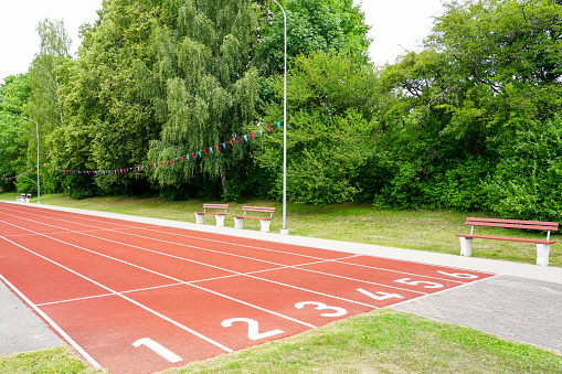 A school stadium running track with a red surface and six numbered lanes, athlete track, red treadmill, perspective view