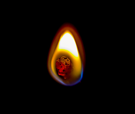 Close-up of igniting matchstick against black background.
