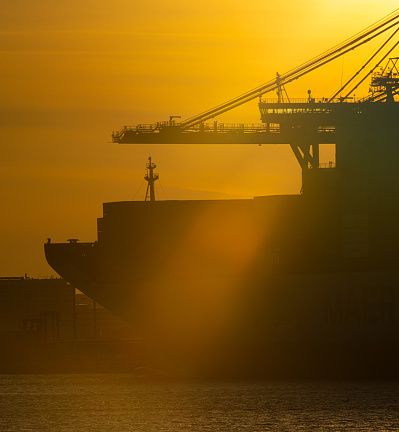 Side bow and bridge of a large container ship at port at sunset.