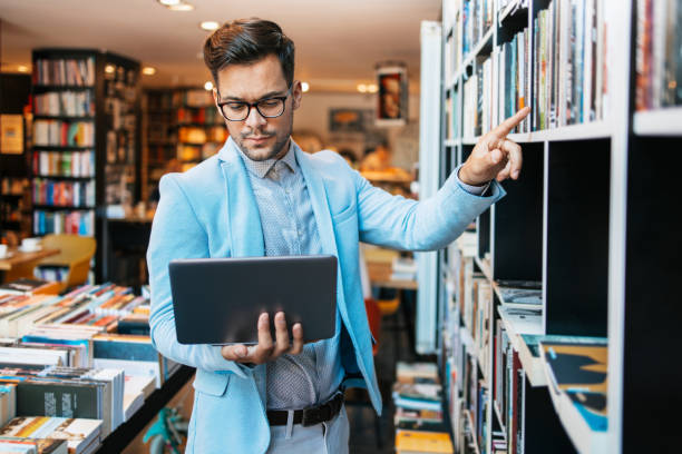 istock Attractive man using laptop in bookstore 1728253774