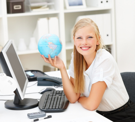 Young girl is using a computer and looking at the camera.