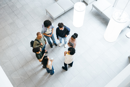 Over head photo of teacher greeting university students in modern faculty lobby