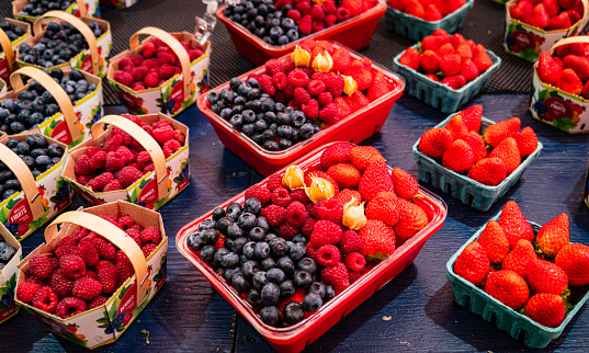 baskets of fresh fruit arranged for sale: strawberries, blueberries, ground cherries in their husks and raspberries