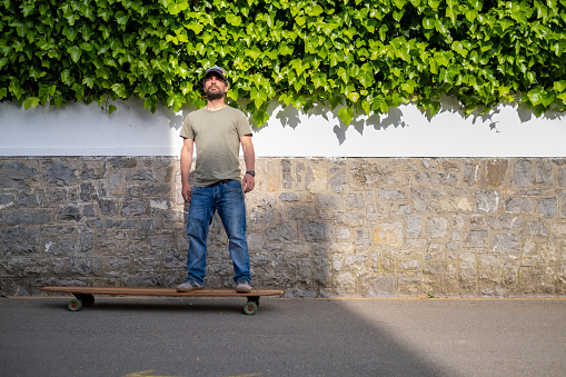 A young casual man standing on skateboard outdoors in the street