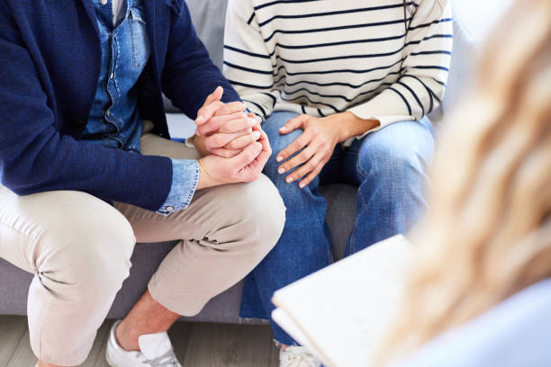 istock Couple holding hands and sitting at marriage counseling session 1728294540