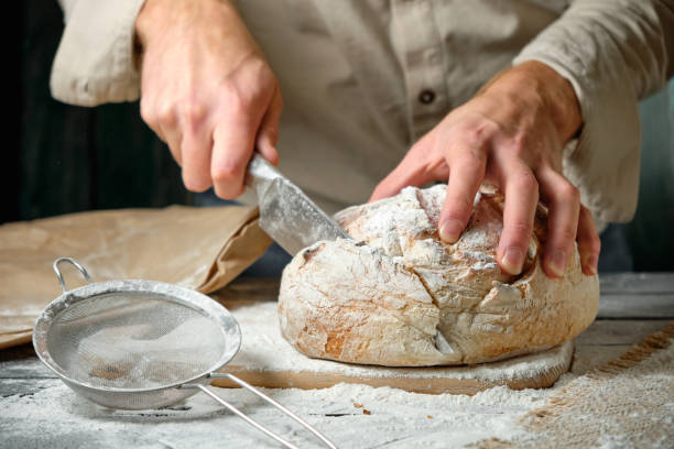 istock man slices fresh bread on a wooden table 1728302835