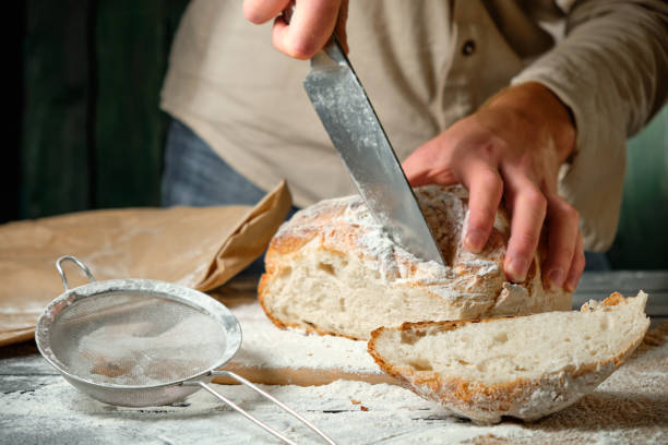 istock man slices fresh bread on a wooden table 1728302841