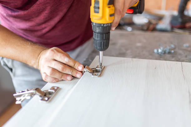 istock Man holding cordless screwdriver machine and screws lie for screwing a screw assembling furniture at home 1728304485