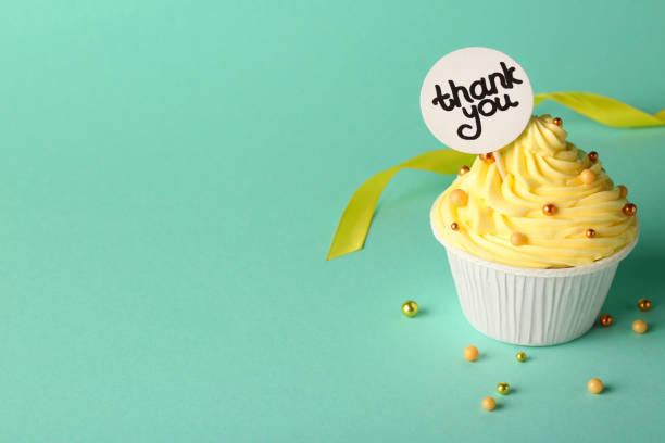 istock Tasty cupcake and note with phrase Thank You on turquoise background, space for text 1728307921