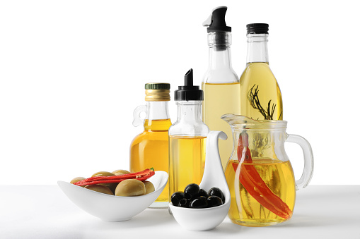 Many different cooking oils and olives on white background