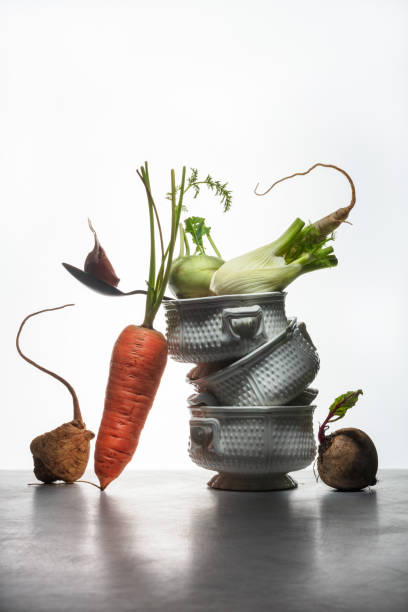 Variety of root vegetables. Balancing natural fresh herbs, vegetables and bowls on a white background and table. Healthy food. Spotlight. Art food photography. Balancing food. Shallow depth of field.