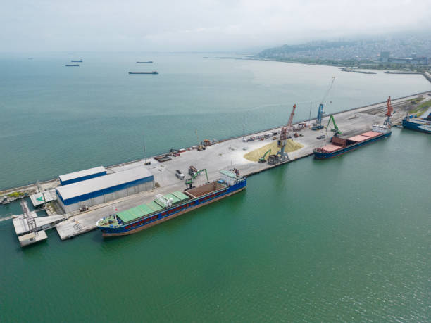 istock Loading operations with a portal crane in a warehouse in the port.Grain transshipment from cargo ship to truck holds 1728320234