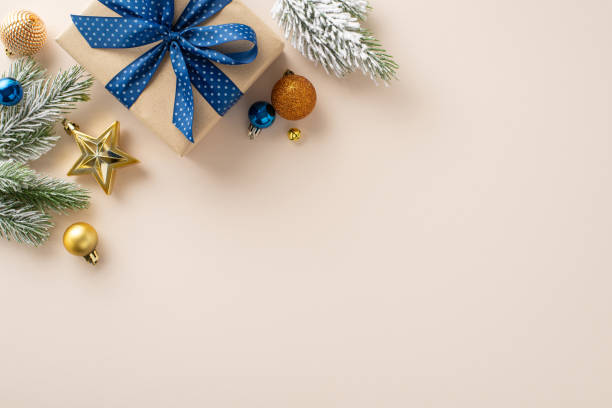 istock Commemorate New Year in elegance. Top-view perspective of carefully wrapped giftbox, chic tree ornaments, glittery balls, seasonal adornments on beige backdrop, awaiting your personal message or promo 1728335037