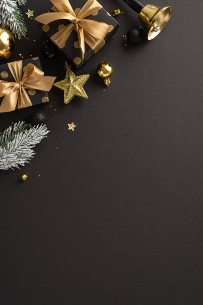 istock Upscale Yuletide dreams theme. Top view vertical shot of sumptuous gift parcels, expensive tree ornaments, balls, shiny confetti, bell, frost-covered evergreen sprigs on dark backdrop for festive ad 1728335082