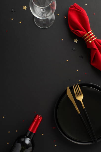 istock Unforgettable Black Friday dining deal: vertical top view sophisticated table setup, including dishes, red napkin, wine bottle, glass, dazzling confetti on black surface. Great for promotional needs 1728335112