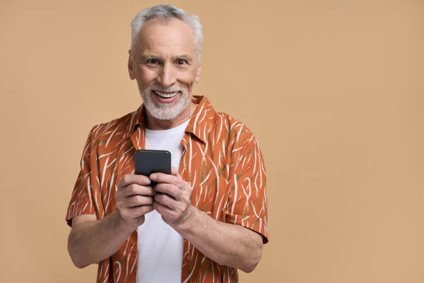 istock Smiling senior man using phone, browsing Internet, scrolling news feed, checks social media content 1728335266