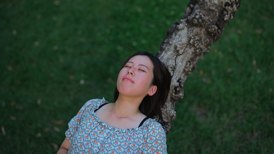 A portrait of an Asian woman relaxing in nature.