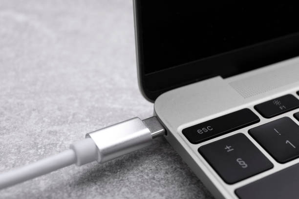 istock USB cable with type C connector plugged into laptop port on grey table, closeup 1728335687