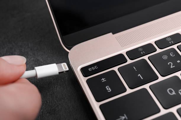 istock Woman plugging USB cable with lightning connector into laptop port on dark table, closeup 1728335829