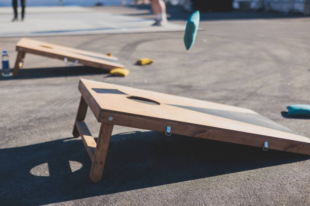 istock Cornhole game set, process of throwing bean bags, kids children tossing bean sacks, corn hole  in the backyard, wooden boards for corn-hole tournament in the summer sunny day 1728339418