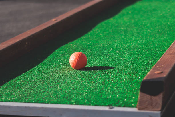 istock Mini golf course, process of playing miniature golf on a green artificial turf in a summer sunny day, eqipment for mini-golf in a golf club resort, club and ball 1728341092