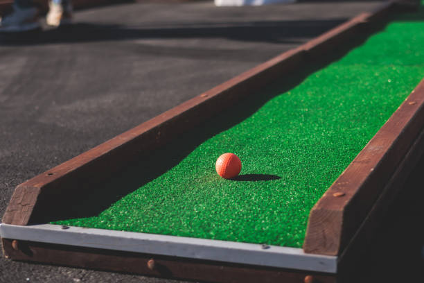 istock Mini golf course, process of playing miniature golf on a green artificial turf in a summer sunny day, eqipment for mini-golf in a golf club resort, club and ball 1728341093