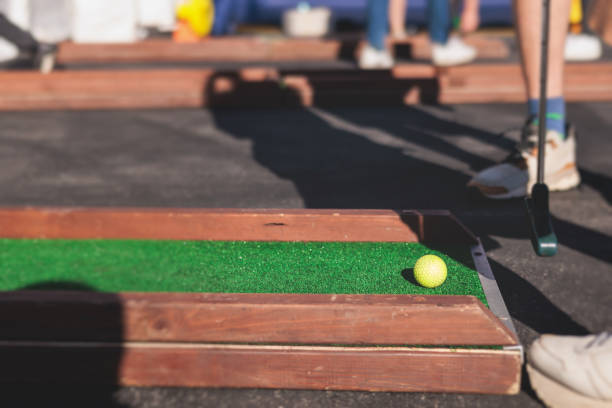 istock Mini golf course, process of playing miniature golf on a green artificial turf in a summer sunny day, eqipment for mini-golf in a golf club resort, club and ball 1728341604