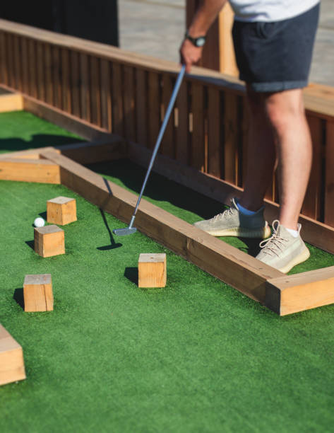 istock Mini golf course, process of playing miniature golf on a green artificial turf in a summer sunny day, eqipment for mini-golf in a golf club resort, club and ball 1728341613