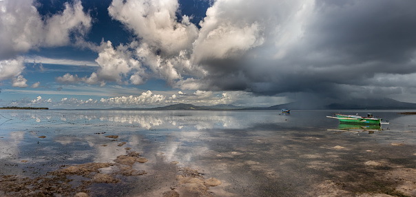A thunderstorm is pouring over Manado Island while the sea is very calm on Bunaken Island in North Sulawesi.