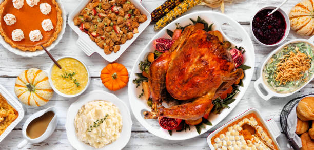 istock Delicious Thanksgiving turkey dinner. Overhead view table scene on a rustic white wood banner background. Turkey, mashed potatoes, stuffing, pumpkin pie and sides. 1728350623