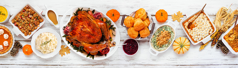 Delicious Thanksgiving turkey dinner. Top view table scene on a rustic white wood banner background. Turkey, mashed potatoes, stuffing, pumpkin pie and sides.