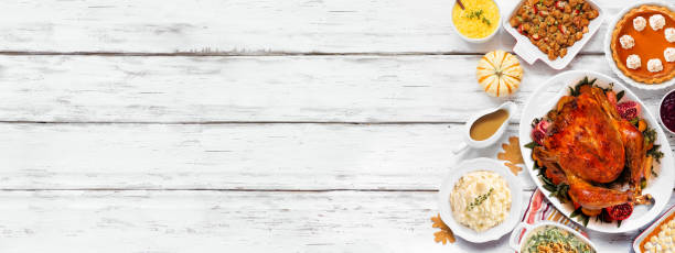 istock Traditional Thanksgiving turkey dinner. Top view side border on a rustic white wood banner background. Turkey, mashed potatoes, stuffing, pumpkin pie and sides. 1728351141