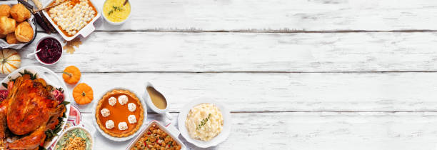 istock Traditional Thanksgiving turkey dinner. Top down view corner border on a rustic white wood banner background. Turkey, mashed potatoes, stuffing, pumpkin pie and sides. 1728351164