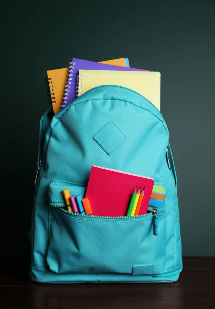 istock Backpack with different school stationery on white table near chalkboard 1728353910
