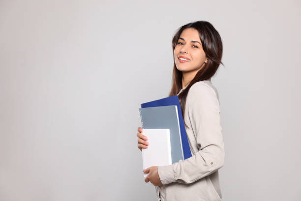 istock Happy young teacher with books on light grey background. Space for text 1728370455