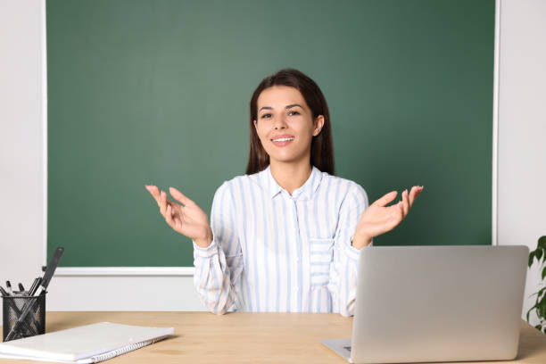 istock Happy young teacher explaining something at table in classroom 1728371557