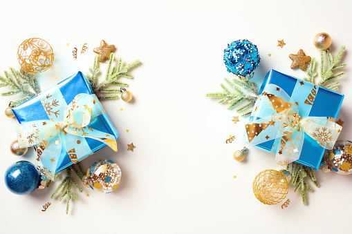 Christmas flat lay composition with luxury gifts, fir branches, gold and blue decorations on white background.