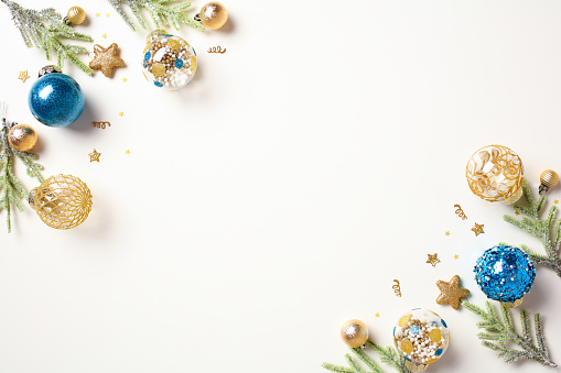 Christmas frame of fir branches with gold and blue ornaments on white table. Flat lay, top view, copy space.