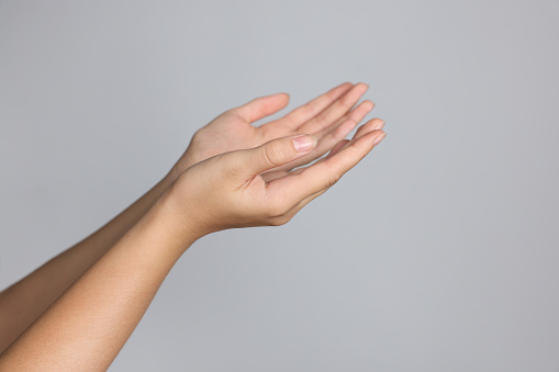 Woman stretching hands against light grey background, closeup. Space for text