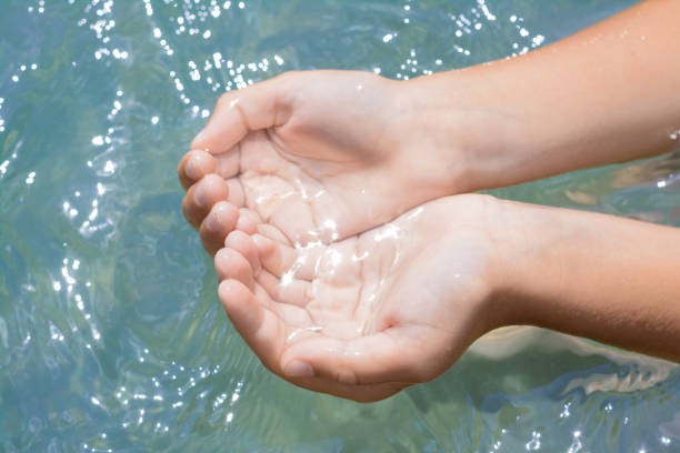istock Kid holding water in hands above sea outdoors, closeup 1728400464