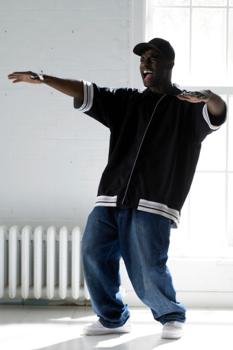 a young african american man in a dance type pose as he yells.