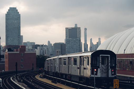 New York skyline at sunset seen from a subway station with a train approaching.