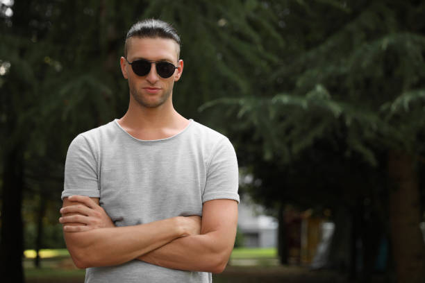 istock Handsome young man in stylish sunglasses at park, space for text 1728451383