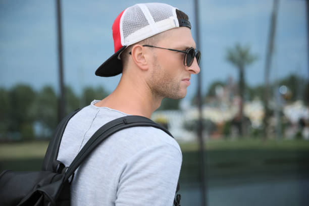 istock Handsome young man with stylish sunglasses and backpack near reflection surface outdoors 1728453010